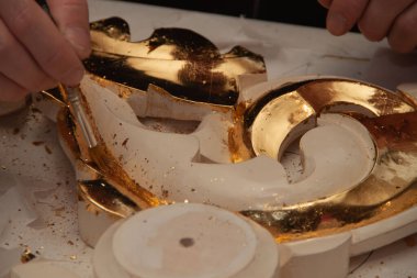 Sanatçı süsü gerçek altınla süslemiş. Kuyumcu. Eller ve fırça