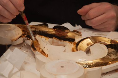 Sanatçı süsü gerçek altınla süslemiş. Kuyumcu. Eller ve fırça