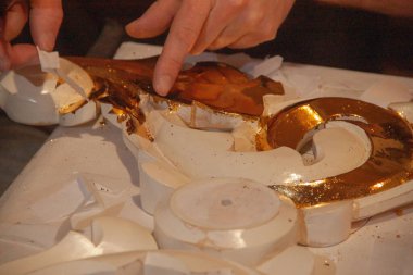 Sanatçı süsü gerçek altınla süslemiş. Kuyumcu. Eller ve fırça