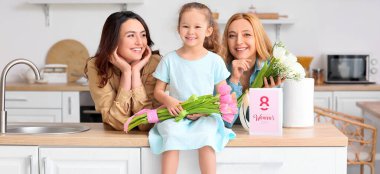 Genç bir kadın, Uluslararası Kadınlar Günü 'nde evde çiçekli küçük kızı ve annesi.