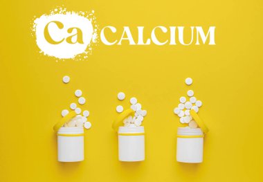 Sarı arka planda kalsiyum haplı şişeler.