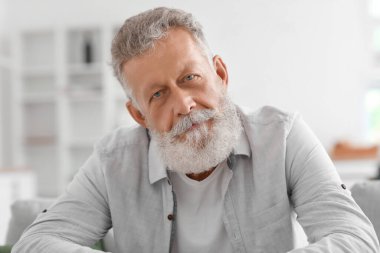 Mutfakta koltukta oturan yaşlı sakallı adam, yakın plan.