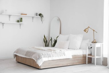 Büyük yataklı, raflı ve aynalı aydınlık yatak odasının içi.