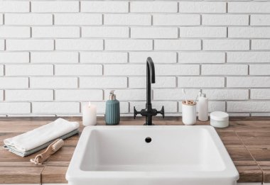 Banyo aksesuarları yanan mum ve lavabo beyaz tuğla duvarın yanında.