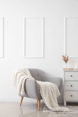 Aydınlık oturma odasının içinde ekoseli gri koltuk