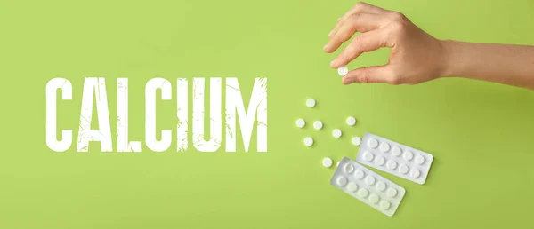 stock image Female hand with calcium pills on green background