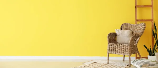 有靠垫的柳条扶手椅 室内盆栽和靠近黄色墙壁的梯子 有文字空间 — 图库照片