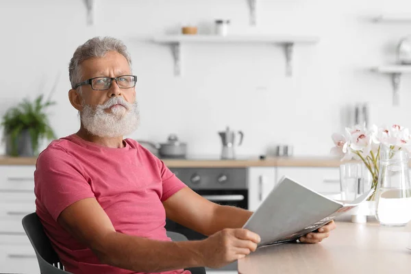 Senior Man Met Bril Leesblad Aan Tafel Keuken — Stockfoto