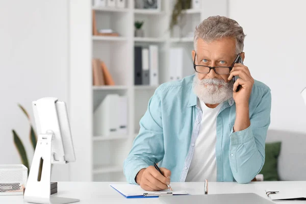 Senior Man Talking Mobile Phone Writing Table Office — Stock Photo, Image