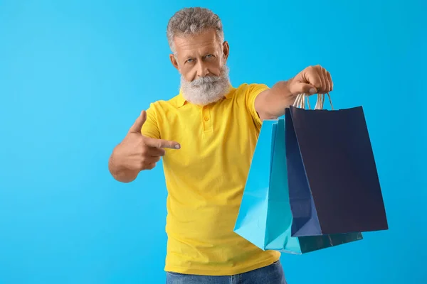 Старший Мужчина Указывает Сумки Покупок Синем Фоне — стоковое фото