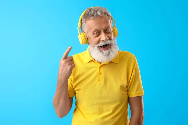 Starszy Brodaty Mężczyzna Wskazując Słuchawki Niebieskim Tle — Zdjęcie stockowe