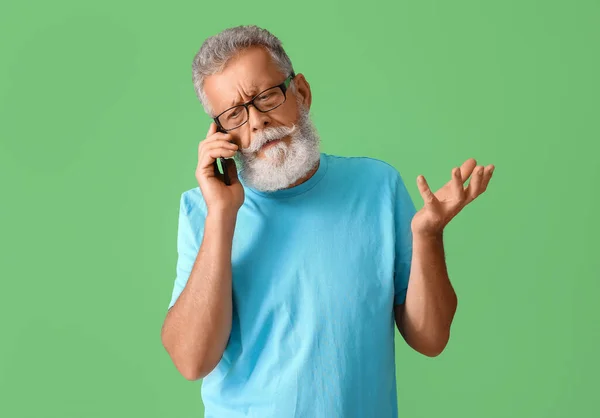 Zły Senior Rozmawia Przez Telefon Komórkowy Zielonym Tle — Zdjęcie stockowe