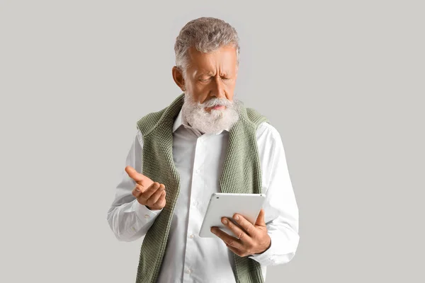 Przemyślany Dojrzały Mężczyzna Korzystający Tabletu Szarym Tle — Zdjęcie stockowe