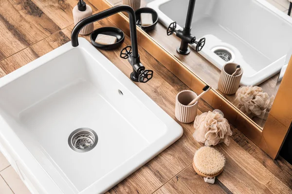 Bath accessories and sink on table near mirror