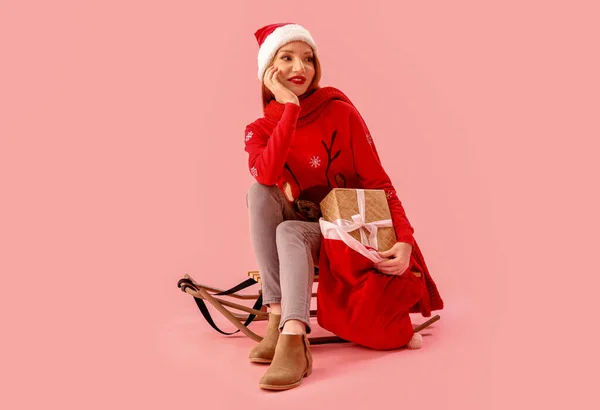 Beautiful Young Woman Santa Hat Bag Gifts Sledge Pink Background — Stock Photo, Image