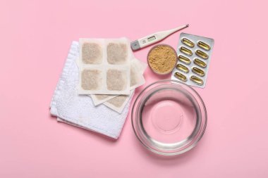 Su dolu hardal alçıları, pembe arka planda termometre ve havlu.