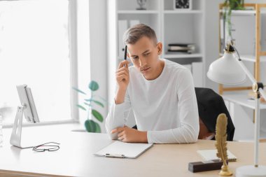 Ofiste oturan kalemli düşünceli genç adam.