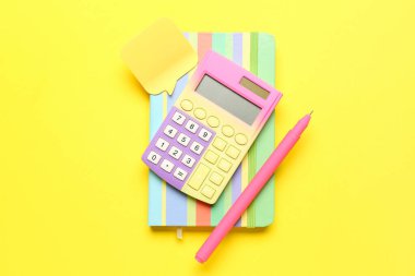 Hesap makinesi, defter, renk arkaplanı üzerine kalem ve yapışkan not. Para tasarruf kavramı