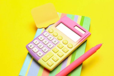 Hesap makinesi, defter, renk arkaplanı üzerine kalem ve yapışkan not. Para tasarruf kavramı