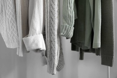 Açık renkli duvarın yanında örülmüş süveterler var, yakın plan.