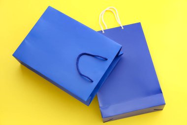 Sarı arka planda mavi alışveriş torbaları. Kara Cuma indirimi