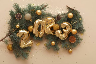 Şekil 2023 balonlardan, kurutulmuş turunçgillerden, köknar dallarından ve bej arka planda Noel toplarından yapılmıştır.