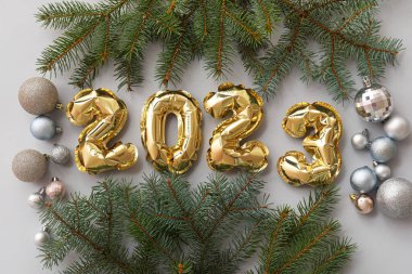 Şekil 2023 balonlardan, köknar dallarından ve gri arka planda Noel toplarından yapılmıştır.