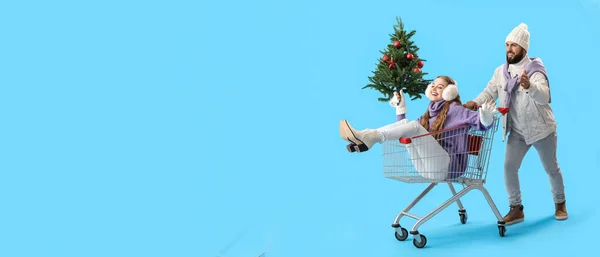 Glückliches Junges Paar Mit Weihnachtsbaum Und Einkaufswagen Auf Hellblauem Hintergrund — Stockfoto