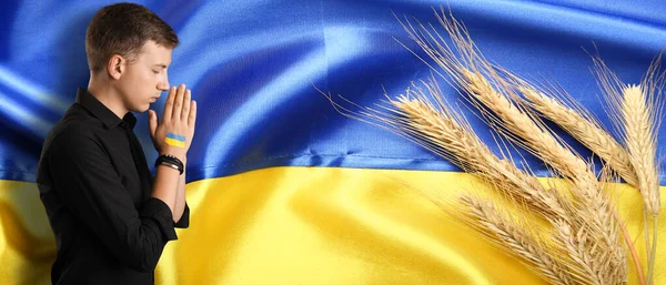 年轻男子高举乌克兰国旗祈祷 — 图库照片
