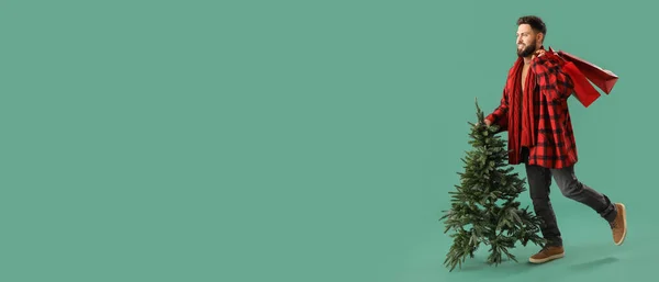 Schöner Mann Mit Weihnachtsbaum Und Einkaufstaschen Auf Grünem Hintergrund Mit — Stockfoto