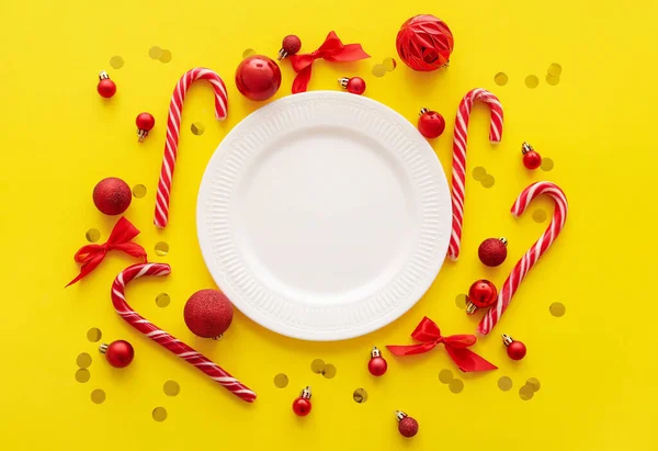 Weißer Teller Mit Rotem Weihnachtsdekor Und Konfetti Auf Gelbem Hintergrund — Stockfoto
