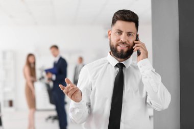 Ofiste cep telefonuyla konuşan yakışıklı bir banka müdürü.