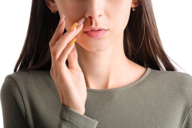 Beyaz arka planda burnu kanayan genç bir kadın, yakın plan.