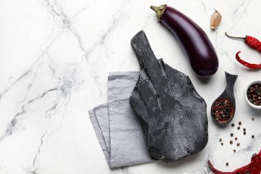 Siyah tahta kesme tahtası, peçete, baharatlı kaşık ve grunge arka planda patlıcan.