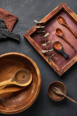 Koyu arkaplanda ahşap mutfak aletleri ve okaliptüs dalı