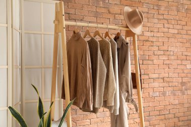 Odanın tuğla duvarının yanında kalın kadın giysileriyle dizilin.