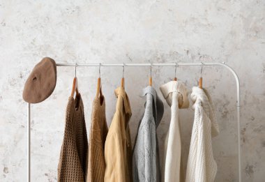 Kalın kadın giysileriyle aydınlık duvarın yanında diz.