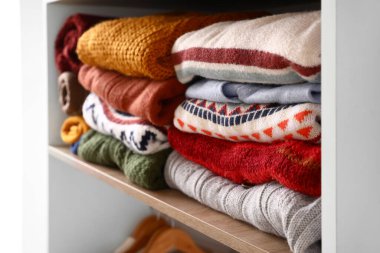 Dolaptaki rafta sıcak örülmüş süveterler, yakın plan.