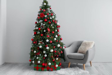 Hediyeli Noel ağacı ve ışık duvarının yanındaki koltuk.
