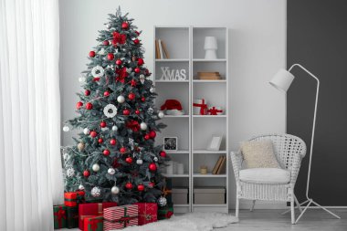 Oturma odasının içinde Noel ağacı, raf ünitesi ve koltuk var.
