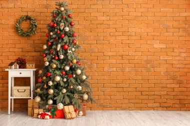Küp takvimli masa, Noel ağacı ve tuğla duvarın yanında hediyeler.