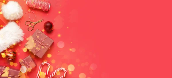 Komposition Mit Weihnachtsgeschenken Weihnachtsmütze Dekorationen Und Schere Auf Rotem Hintergrund — Stockfoto