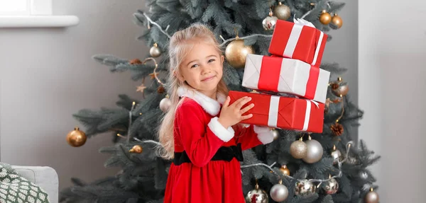 漂亮的小女孩穿着圣诞老人的服装 家里有圣诞礼物 — 图库照片