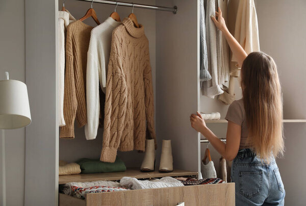 Woman taking warm sweater in wardrobe