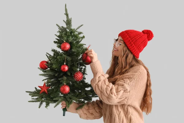若いです女性クリスマスツリーとグレーの背景に装飾 — ストック写真