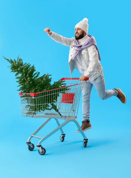 Jóképű Férfi Bevásárlókocsi Karácsonyfa Ugrás Kék Háttér — Stock Fotó