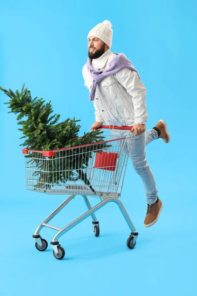 Handsome Man Shopping Cart Christmas Tree Jumping Blue Background — Stock Photo, Image