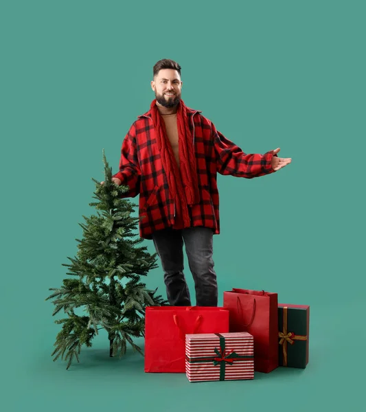 Schöner Mann Mit Weihnachtsbaum Einkaufstaschen Und Geschenken Auf Grünem Hintergrund — Stockfoto