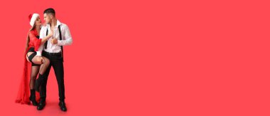 Kırmızı arka planda seksi genç bir çift ve mesaj için yer var. Noel kutlaması