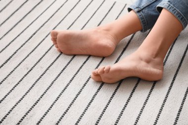 Çizgili halıda çıplak ayaklı kadın, yakın plan.